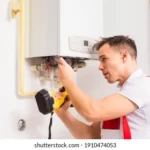 plumber-repairs-boiler-kitchen-260nw-1910474053
